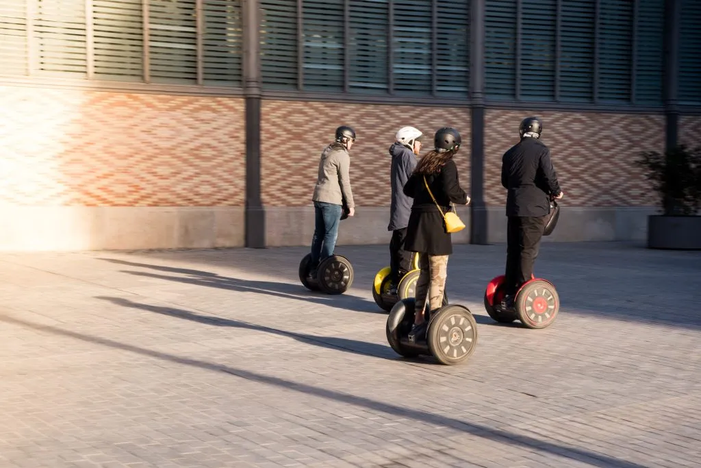 Eine Gruppe von Personen auf umweltfreundlichen Segway-Rollern in einer historischen Straße in Spanien. Touristen, die sich an elektrischen Motorrollern erfreuen.