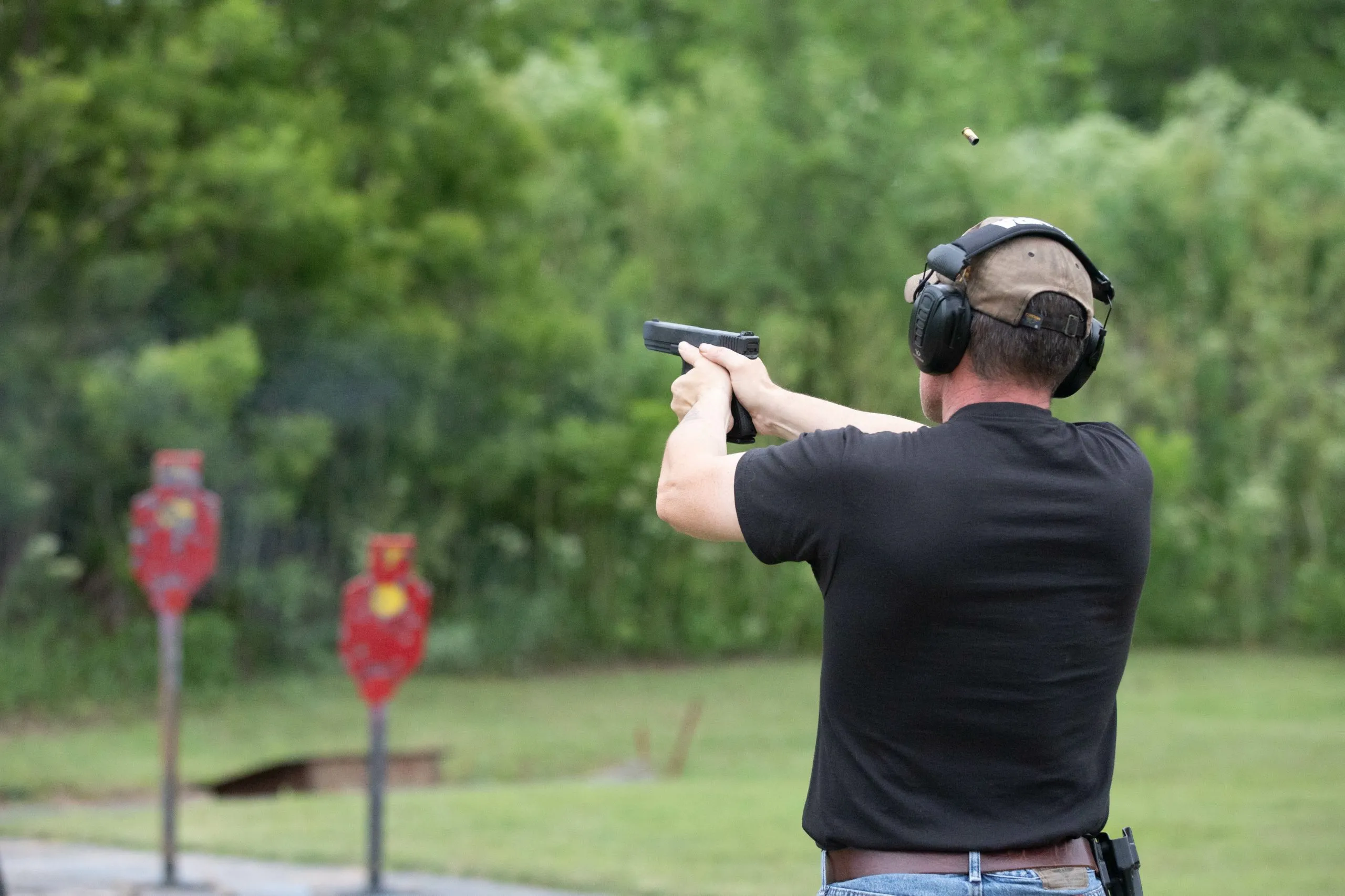 Hombre disparando con una pistola en un campo de tiro al aire libre