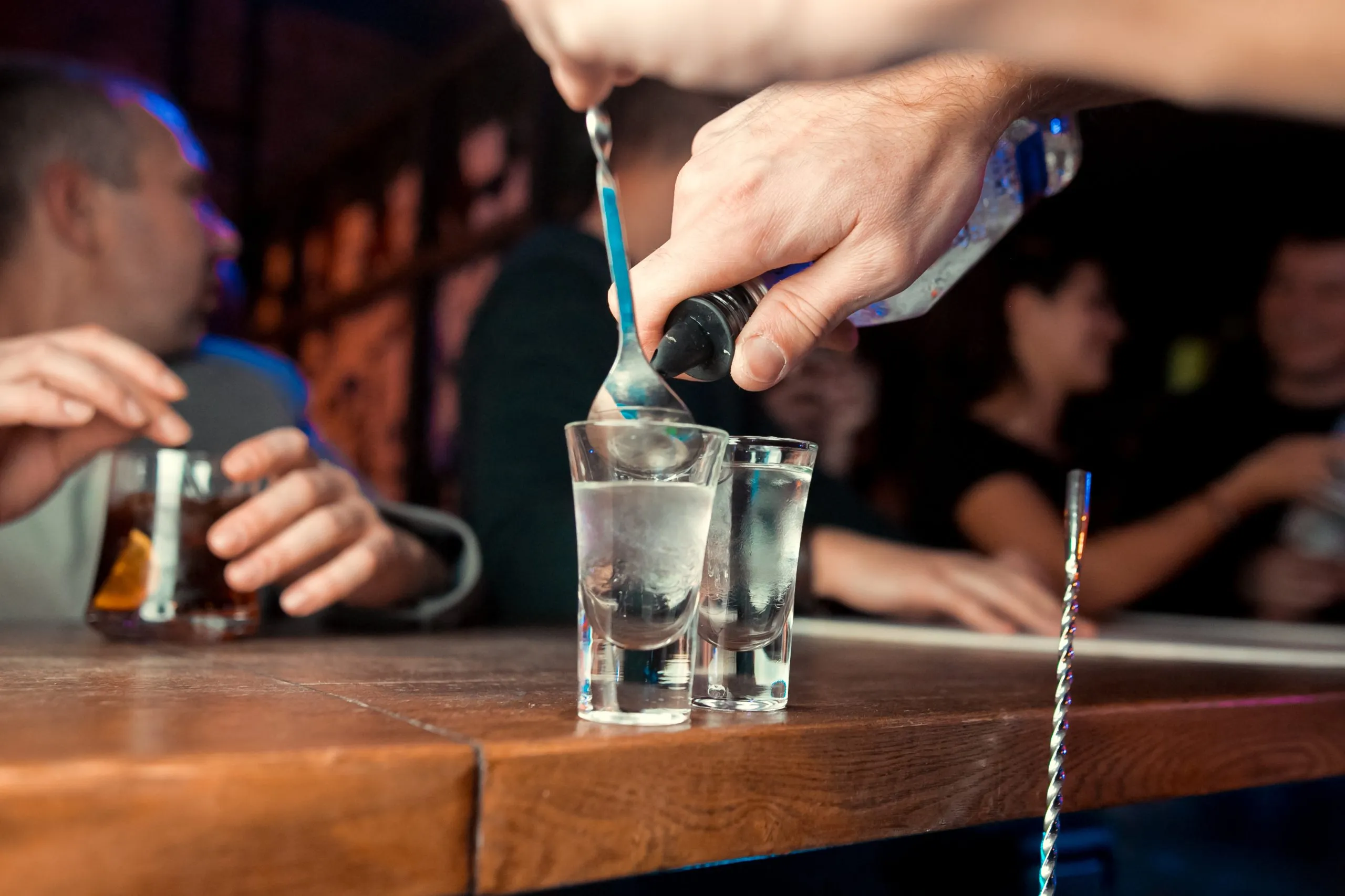 Barman versant de l'alcool fort dans des verres en détail
