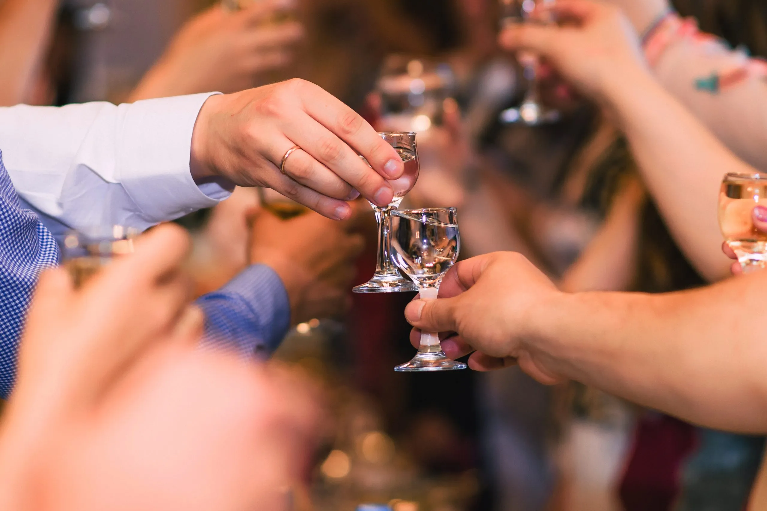 Hände mit Wodkagläsern bei der Feier des traditionellen russischen Feiertags